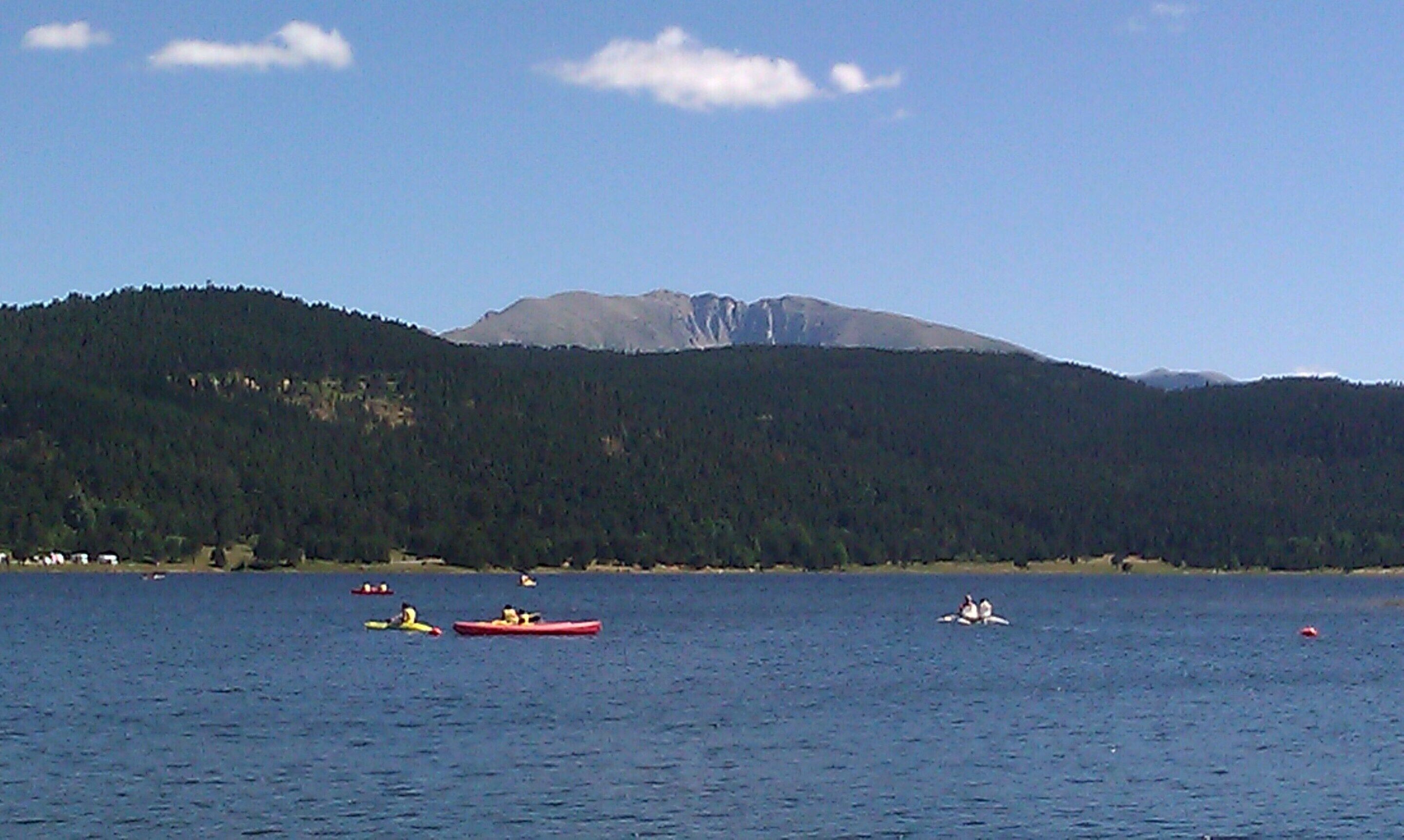 Un lac où l’on peut faire du kayak, une montagne boisée et un ciel dégagé.