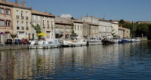 Un canal con barcos amarrados, edificios con balcones y un cielo despejado.