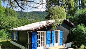 A small house with a tiled patio, a wooden table, and blue shutters. - Chalet With Garden in the Pyrenees (Roquefort-de-Sault)