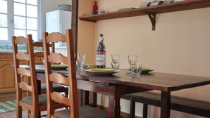 A wooden dining table with chairs, a bottle of water, and empty glasses. - Chalet With Garden in the Pyrenees (Roquefort-de-Sault)