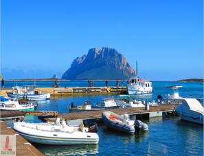 Boats dock at the marina, surrounded by calm waters and a scenic rocky island.
