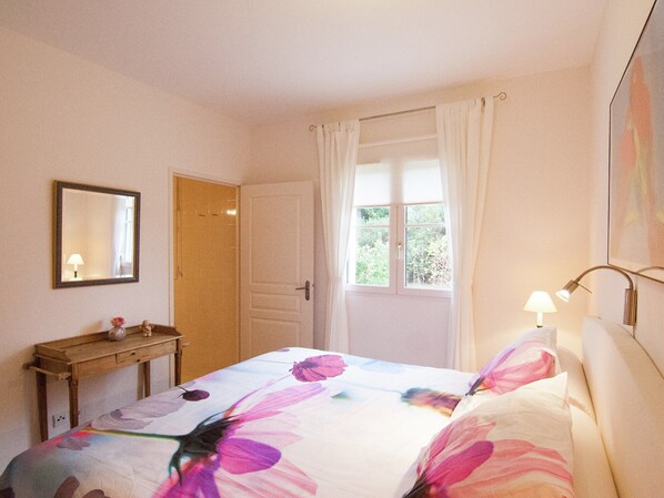 A bedroom with a bed, a bedside table, a mirror, a window with curtains, and a lamp. - Luxury Villa With Heated Pool on Golf With Lots of Privacy and Panoramic Views (Rouzede)