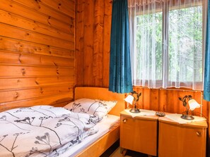 A wooden cabin room with a bed, a nightstand, and a window with curtains. - Cozy Chalet in Obsteig With Terrace (Mieming)
