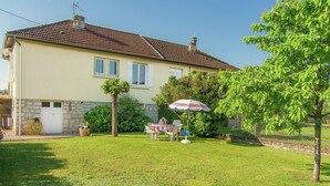 A house with a tiled roof, a stone foundation, a lawn, a table with chairs, and a tree. - Cozy Garden Retreat Malemort (Malemort-sur-Correze)