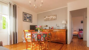 A room with a dining table, chairs, a chandelier, a television, and a bed. - Cozy Garden Retreat Malemort (Malemort-sur-Correze)