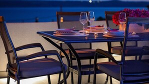 A table set for two with plates, glasses, and a vase of flowers, overlooking a body of water. - Holiday Home With Private Swimming Pool (Jasenice)