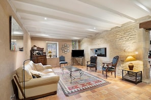 Ein Wohnzimmer mit einer Couch, Sesseln, einem Couchtisch, einem Fernseher und einer Steinwand.