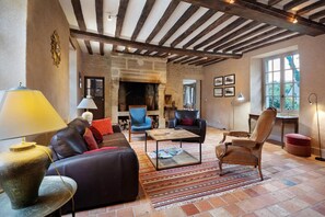 Ein gemütliches Wohnzimmer mit Kamin, Ledersofas, einem Couchtisch und einem gemusterten Teppich.