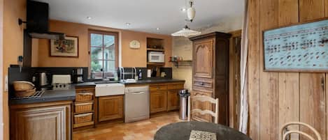 Una cocina compacta con armarios de madera, lavavajillas y un comedor con mesa y sillas.