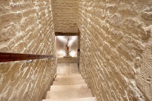 A stone staircase leading to a statue in a narrow corridor. - Elegant Normandy Retreat (Ponts sur Seulles)