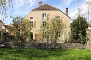 Et toetagers hus med røde mursten, grønne skodder og en stenvæg foran.