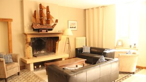 Ein Wohnzimmer mit Kamin, einer Couch, einem Couchtisch und einem Schiffsmodell auf dem Kaminbrett.