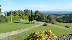 Un paysage verdoyant avec un sentier bien défini, des arbres et une vue lointaine sur une ville.