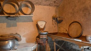 Une cuisine rustique avec des murs en pierre, une table en bois et divers ustensiles de cuisine en métal.