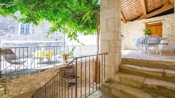 A stone building with a balcony, outdoor seating, and a staircase. - Montclus Charm: Views & Calm (Montclus)