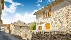 A narrow street with stone buildings, a gate, and a parked car. - Montclus Charm: Views & Calm (Montclus)
