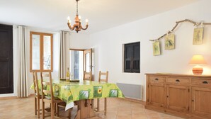 A dining area with a table set for four, a chandelier, and a cabinet with a lamp. - Montclus Charm: Views & Calm (Montclus)
