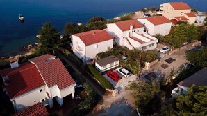 An aerial view of a coastal residential area with houses having red-tiled roofs, a marina with boats, and a clear view of the sea. - Apartment in Seline by the Sea (Starigrad)