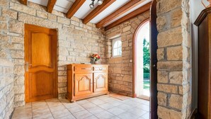 Una habitación con paredes de piedra, una puerta de madera, un armario y un ventanal.