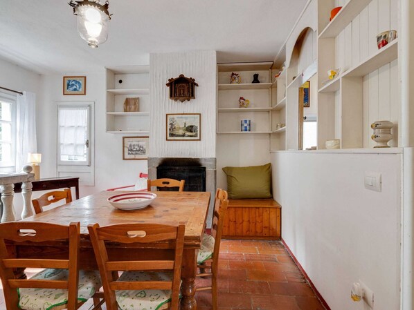 A dining area with a wooden table and chairs, a fireplace, and shelves with various items. - Idyllic Retreat With Shared Pool (San Marcello Piteglio)