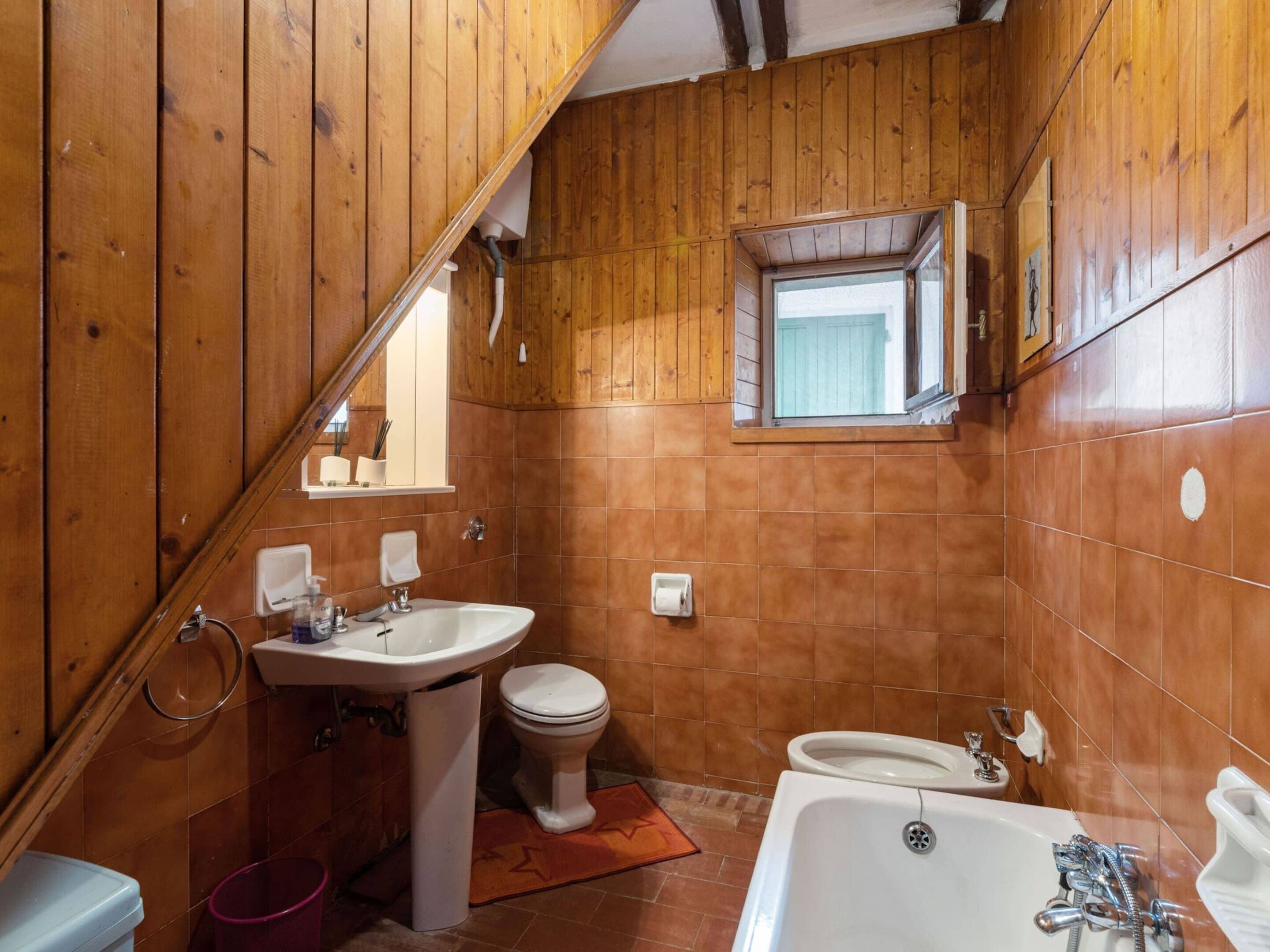 A wooden-paneled bathroom with a sink, toilet, and bathtub.