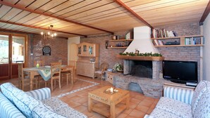 A cozy living room with a fireplace, wooden furniture, and a television. - Exquisite Villa in Cesena With Sauna (Cesena)