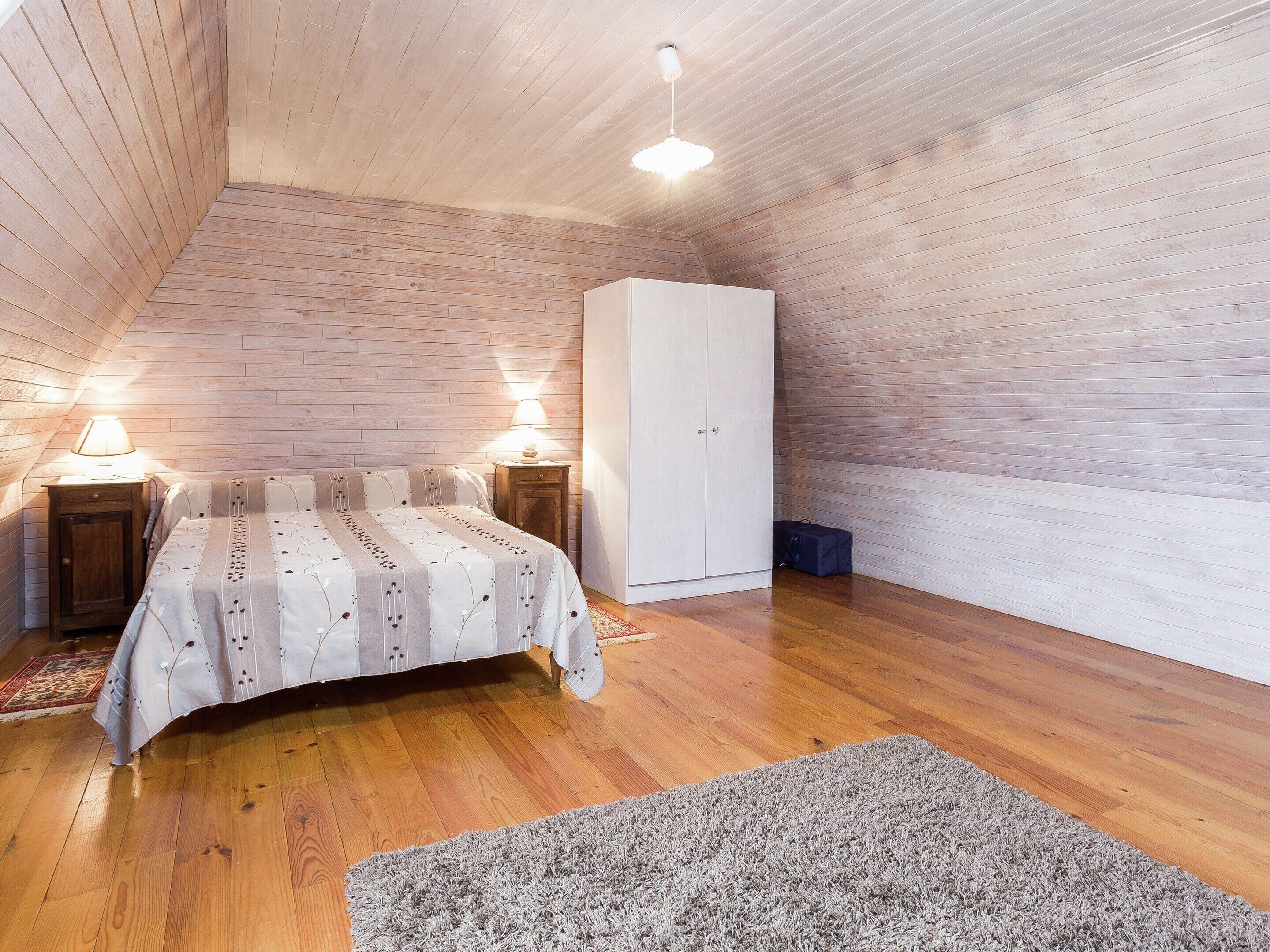 A bedroom with a bed, bedside lamps, a wardrobe, and a wooden floor.