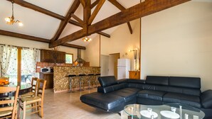 A modern living room with a sectional sofa, a glass coffee table, and a dining area with a table and chairs. - Blanquefort Nature Stay (Blanquefort-sur-Briolance)