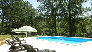 A swimming pool with lounge chairs and an umbrella. - Blanquefort Nature Stay (Blanquefort-sur-Briolance)