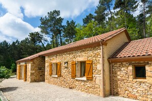 A stone building with a tiled roof, wooden shutters, and a gravel driveway. - Blanquefort Nature Stay (Blanquefort-sur-Briolance)