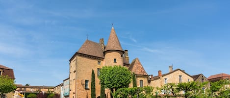 A historic building with a prominent tower, a paved street, and a clear blue sky.