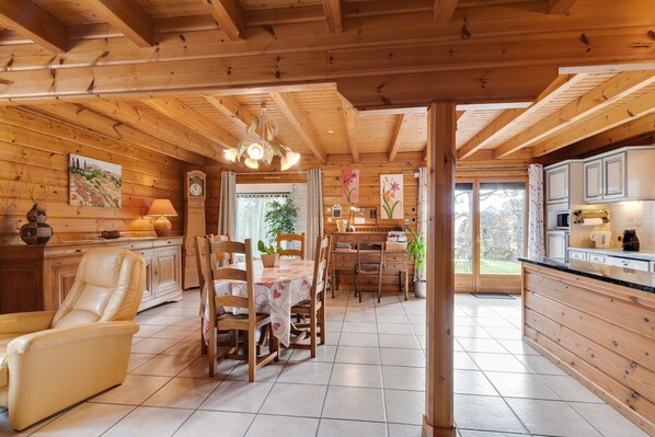 A wooden interior with a dining area, kitchen, and a large window.