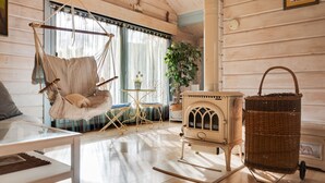 Una habitación acogedora con un sillón colgante, una estufa antigua y una cesta de mimbre.