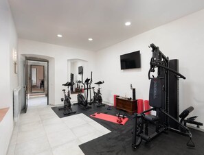 A home gym with exercise equipment, a television, and a door leading to another room. - Villa in Mugello Hills With Private Pool (Vicchio)