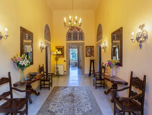 A hallway with ornate chandeliers, wooden chairs, and a patterned rug. - Villa in Mugello Hills With Private Pool (Vicchio)