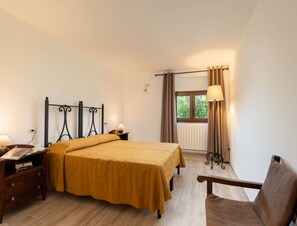 A bedroom with a bed, bedside tables, a chair, a window with curtains, and a radiator. - Villa in Mugello Hills With Private Pool (Vicchio)