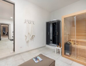 A modern bathroom with a glass-enclosed shower, a wooden sauna, and a towel rack with towels. - Villa in Mugello Hills With Private Pool (Vicchio)