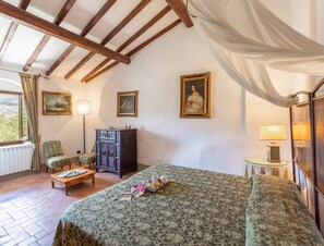 A bedroom with a bed, a nightstand, a lamp, a chair, a cabinet, and a window with curtains. - Villa in Mugello Hills With Private Pool (Vicchio)