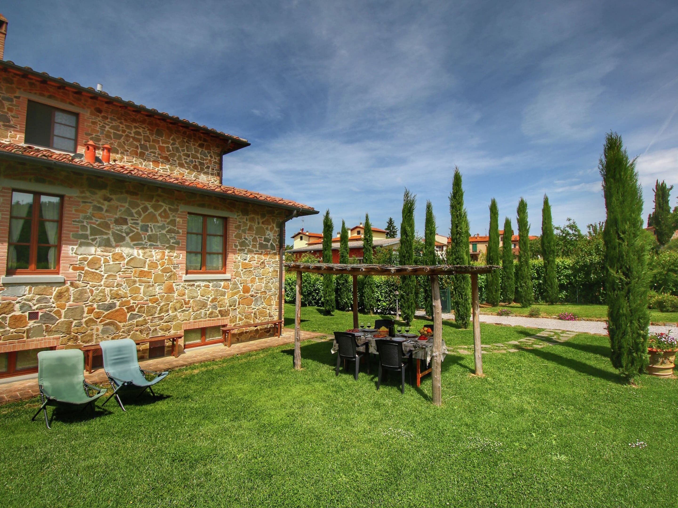 Une maison en pierre dotée d’un patio, d’un espace salon extérieur et d’une pergola.