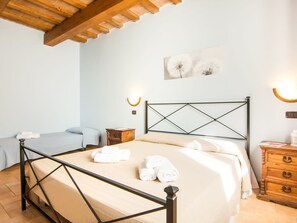 A bedroom with a bed, bedside tables, a nightstand, a wall-mounted light, and a painting. - Agriturismo in the Appenines with Covered Swimming Pool & Hot Tub (Apecchio)