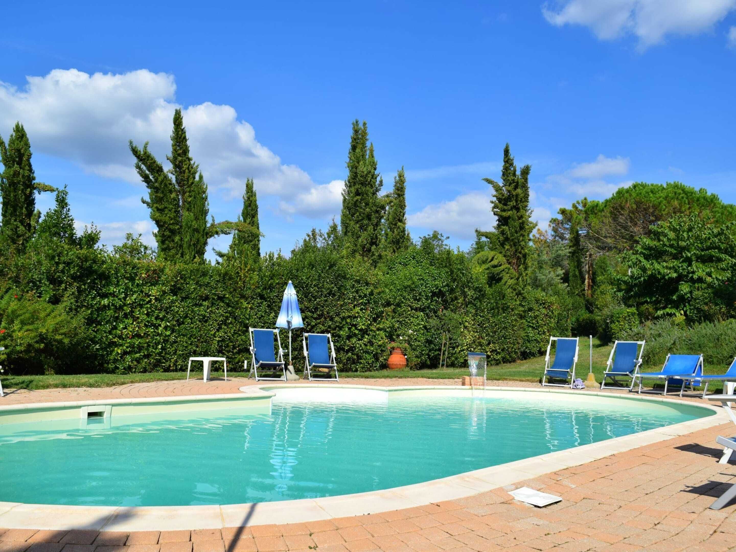 A swimming pool with blue lounge chairs and a blue umbrella.