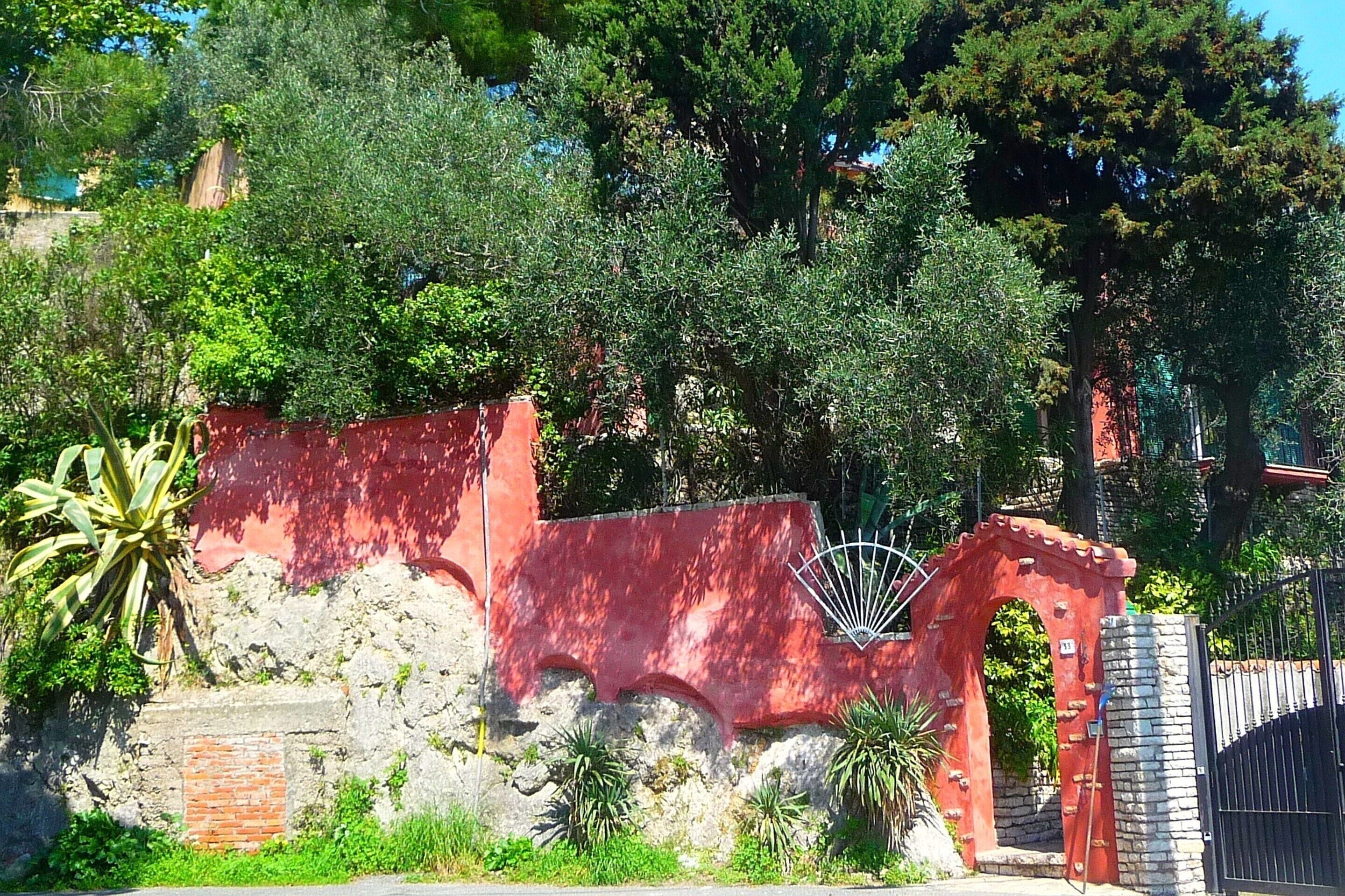 A red wall with a gate and a stone wall.