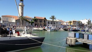 Uma marina com barcos atracados, um farol e edifícios com telhados vermelhos.