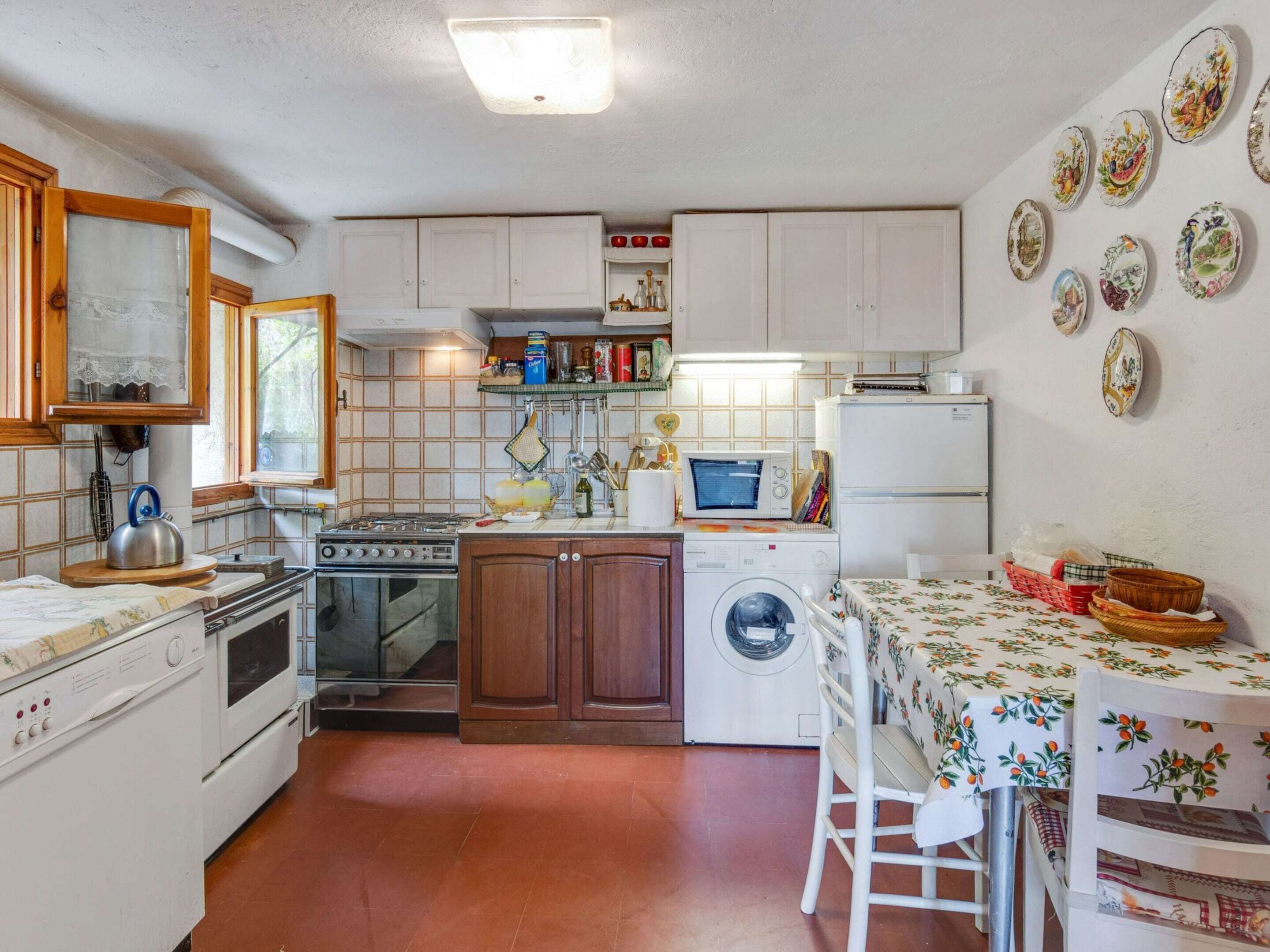 Cocina compacta con estufa, horno, microondas y lavadora. Cuenta con una mesa de comedor con sillas y una ventana con vistas.