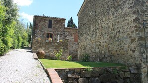 A stone building with a small window and a door, surrounded by greenery and a gravel path. - Idyllic Tuscan Hideaway With Pool and spa (Sesto Fiorentino)