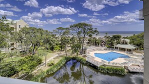 Un complexe hôtelier doté d’une piscine, offrant une vue sur la plage et entouré d’une végétation luxuriante.