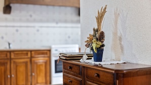 A kitchen with wooden cabinets, a stove, and a decorative plant on a wooden counter. - Charming Child-friendly Holiday Home (La Boussac)