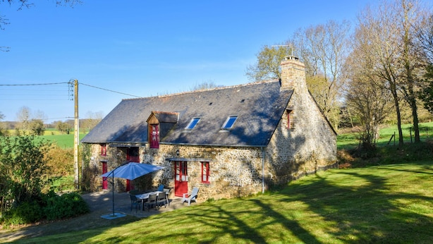 A stone house with a sloped roof, a chimney, and a small patio with outdoor furniture. - Charming Child-friendly Holiday Home (La Boussac)
