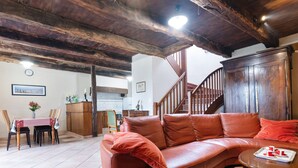 A living room with a leather sofa, wooden dining table, and a staircase. - Charming Child-friendly Holiday Home (La Boussac)