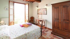 A bedroom with a bed, a chair, a desk, a cabinet, and a painting on the wall. - Belvilla by OYO Giaggiolo (Cerreto Guidi)
